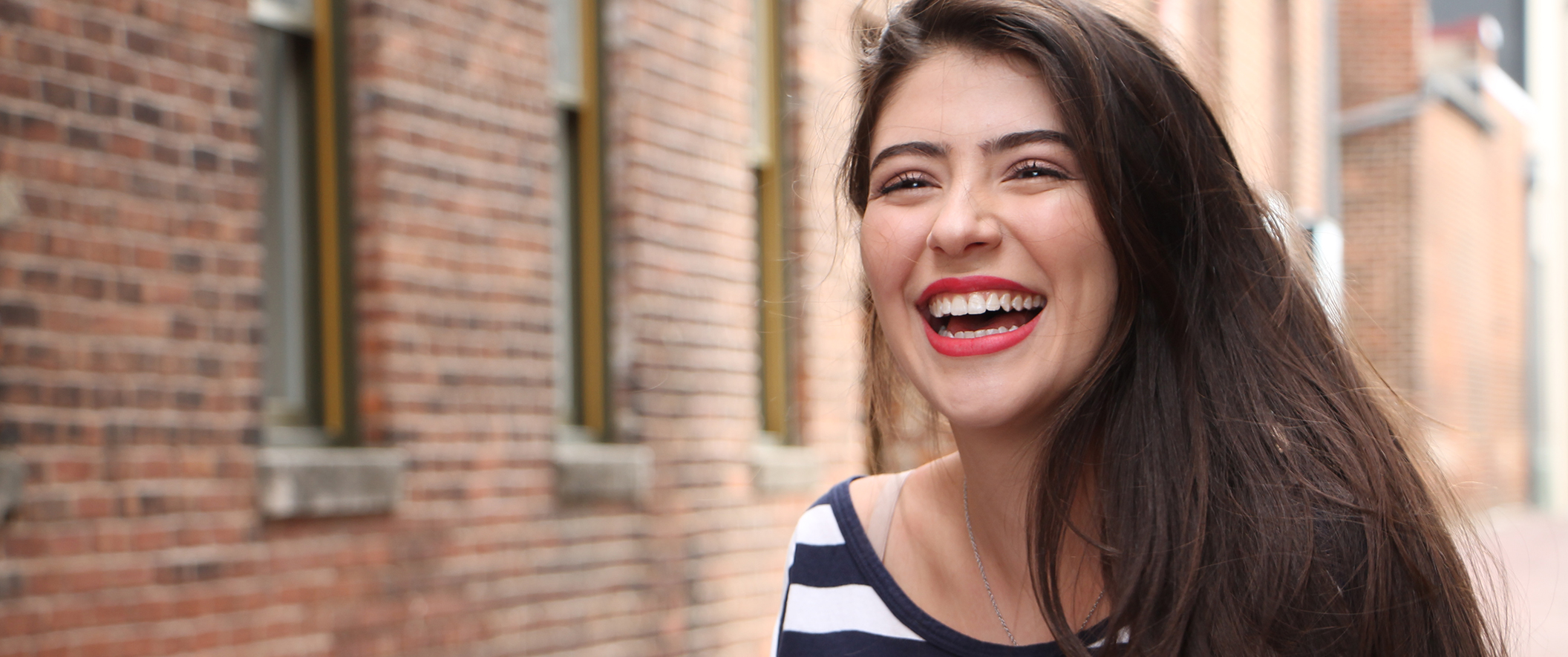 girl smiling in front of brick building